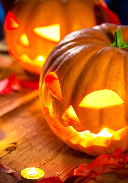 Glowing Halloween pumpkin with candles on a wooden table.