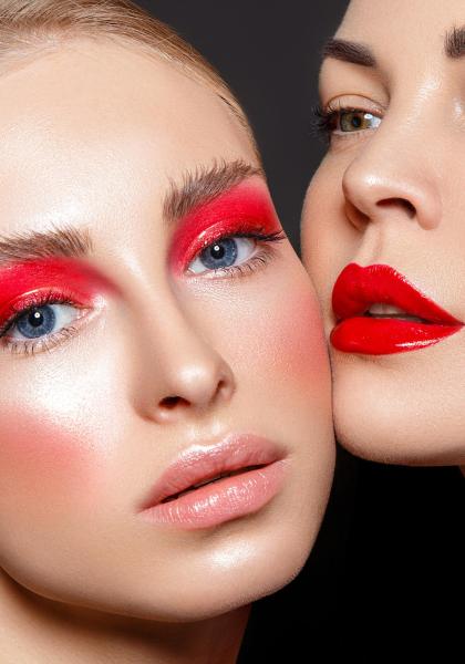 Due donne con trucco audace, rossetto rosso e ombretto rosso intenso.