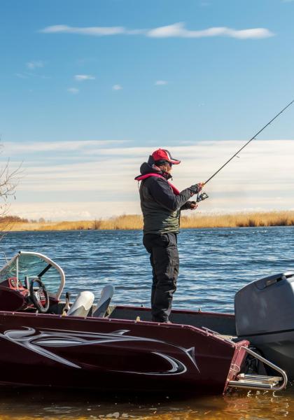 Pescatore su barca rossa in un lago tranquillo.