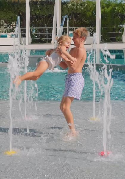 Bambini giocano felici in una fontana vicino alla piscina.