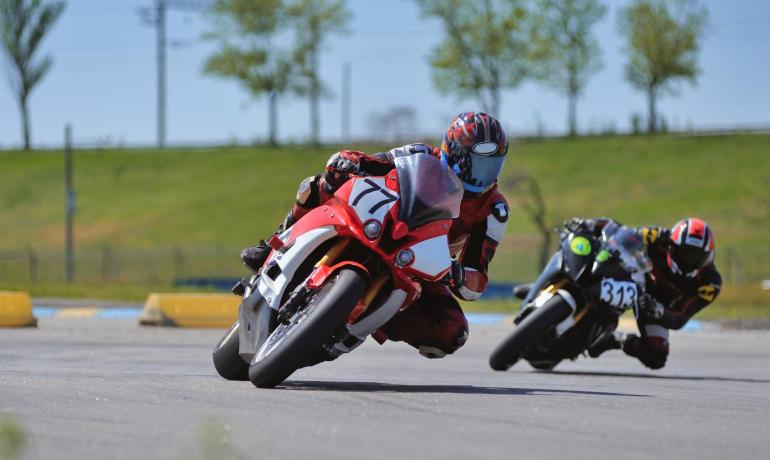 Due motociclisti in gara su una pista, curvando a grande velocità.