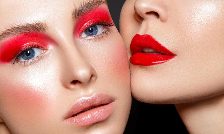 Due donne con trucco audace, rossetto rosso e ombretto rosso intenso.