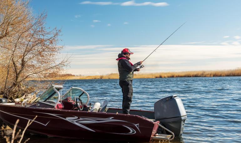 Pescatore su barca rossa in un lago tranquillo.