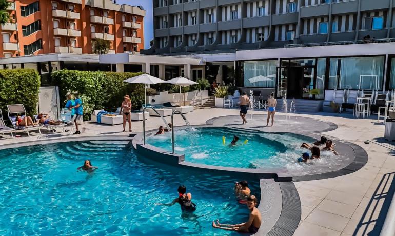 Piscina di un hotel con persone che nuotano e si rilassano.