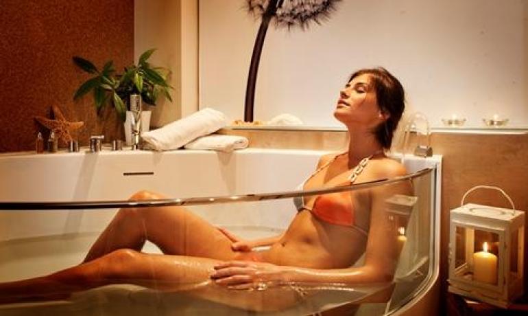 Femme détendue dans la baignoire, ambiance spa chaleureuse.