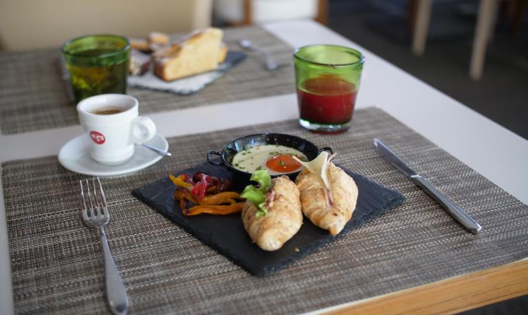 Colazione con cornetti, caffè e succo su tavola apparecchiata.