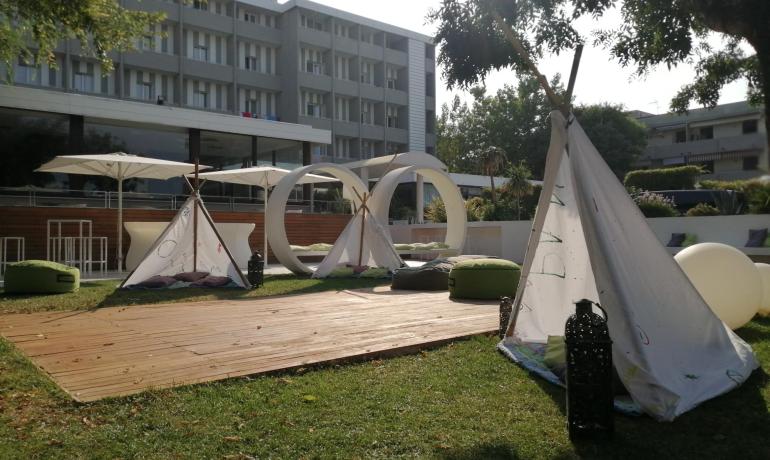 Giardino con tende e sedute all'aperto davanti a un hotel.